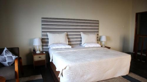 a bedroom with a large bed with white sheets and pillows at Cliffhaven Beach Resort Hotel in Accra