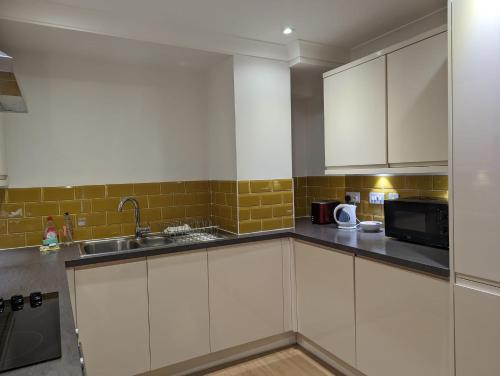 a kitchen with white cabinets and a sink and a microwave at Cosmo Suites in Bracknell