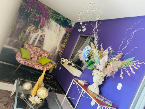 a living room with purple walls and a chair and a glass table at Villa Paradise in Brazil - Praia de Guaratiba Prado-BA in Prado