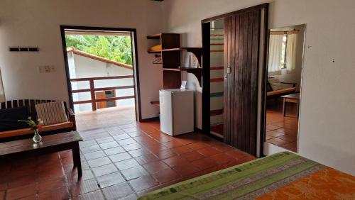 a room with a room with a refrigerator and a table at Pousada Casa da Edinha in Ilha de Boipeba