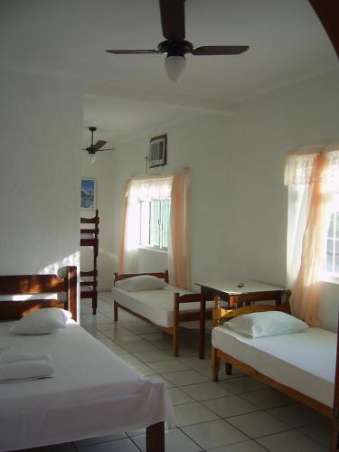 a room with three beds and a ceiling at Hotel Alaska in Peruíbe