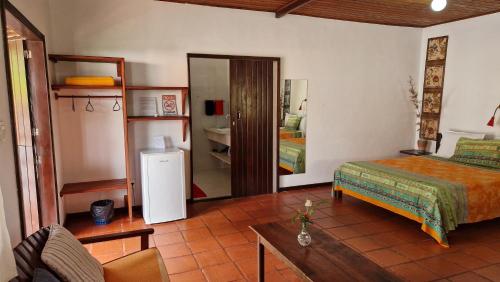 a bedroom with a bed and a room with a refrigerator at Pousada Casa da Edinha in Ilha de Boipeba