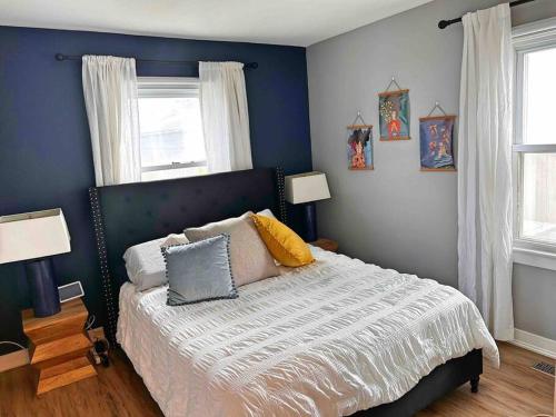 een slaapkamer met een bed met blauwe muren en ramen bij Fenced-In Yard on the East Side in Evansville