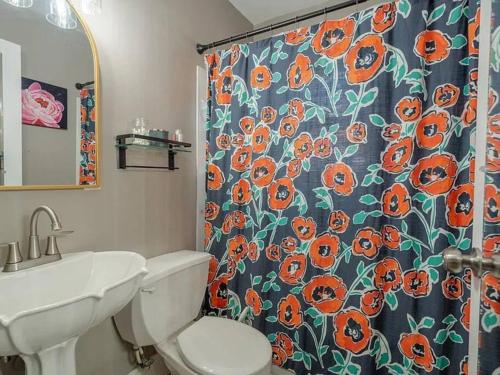 a bathroom with a toilet and a shower curtain with orange flowers at Fenced-In Yard on the East Side in Evansville