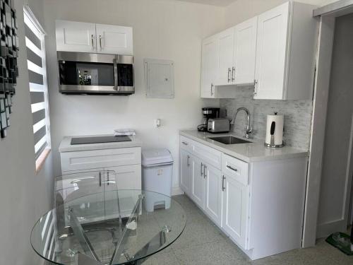 a kitchen with white cabinets and a glass table at Villa Clara SUITE - Little Havana in Miami