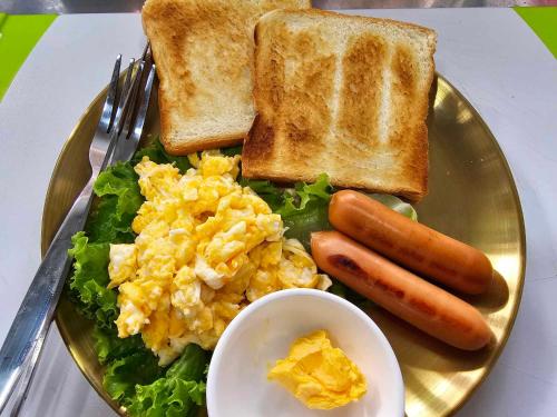 a plate of breakfast food with eggs sausage and toast at Nahm Khao Sok Hostel and Camping in Khao Sok