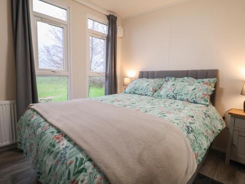 a bedroom with a bed and two windows at Holmside in Market Drayton