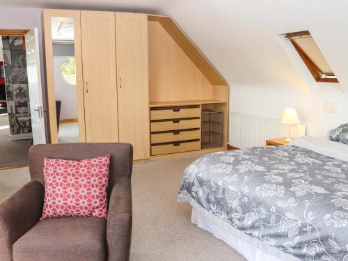 1 dormitorio con cama, silla y vestidor en Seafield, en Ballymoney Cross Roads