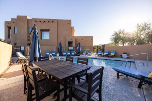 a wooden table and chairs next to a swimming pool at Residence 1: The Villas At Troon North in Scottsdale