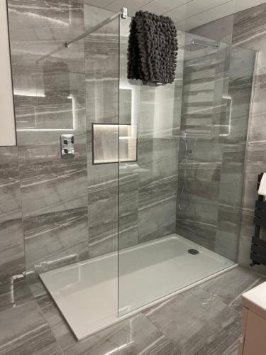 La salle de bains est pourvue d'une douche avec une porte en verre. dans l'établissement Druid House B&B, à Inverness