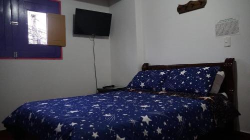 a bedroom with a bed with a blue blanket with stars at Hostal Palmas De Cocora in Salento