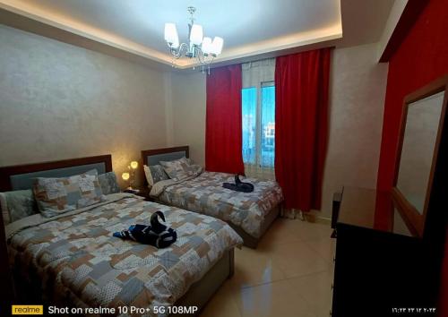 Sharm Hills Resort في شرم الشيخ: سريرين في غرفة مع ستائر حمراء