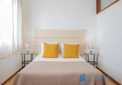 ein Schlafzimmer mit einem Bett mit gelben Kissen und 2 Tischen in der Unterkunft Porto Sé Classic Terrace Apartment in Porto