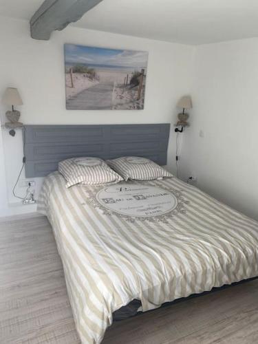 een bed in een slaapkamer met een foto aan de muur bij La Guitoune in Beuzeville