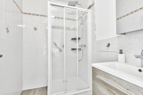 La salle de bains blanche est pourvue d'une douche et d'un lavabo. dans l'établissement Nice apartment, 15min from Paris, à Antony