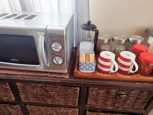 a counter with a microwave and some cups and jars at Adorable Designs in Pretoria