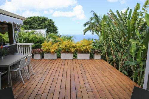 a deck with plants and a table and chairs at Villa Ô Perchée, Vue Mer Panoramique et Piscine Privée in Pointe-Noire