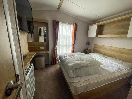 a small bedroom with a bed and a window at Lovely 6 Berth Caravan At Caldecott Hall Country Park, Norfolk Ref 91010c in Great Yarmouth