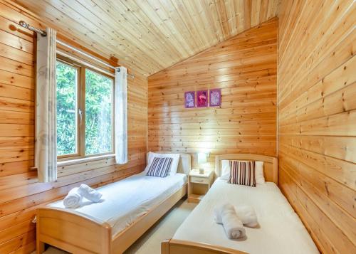 a room with two beds in a wooden cabin at Ruby Country Lodges in Beaworthy