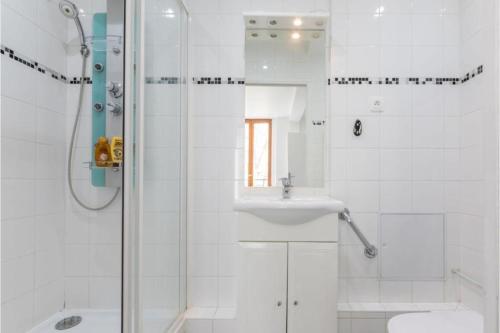 a white bathroom with a shower and a sink at Appartement Montparnasse in Paris