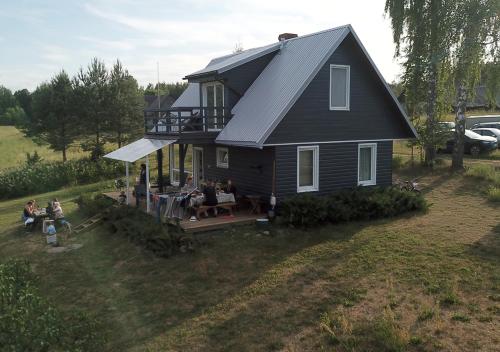 - une vue sur une maison avec des personnes assises sur une terrasse couverte dans l'établissement Meza Skuki, à Vabole