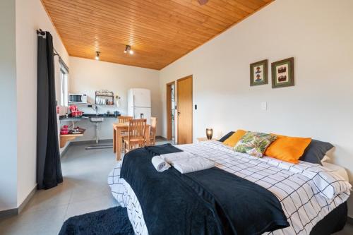 a bedroom with a large bed and a kitchen at Studios Pinhal in Santo Antônio do Pinhal
