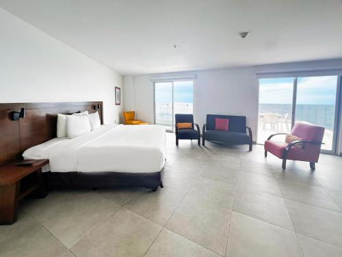 a bedroom with a large white bed and chairs at Park Inn by Radisson Mazatlan in Mazatlán