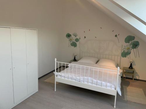 a bedroom with a white bed with flowers on the wall at Citywohnung Würselen in Würselen