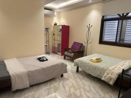 um quarto com duas camas e uma cadeira em Cozy Mountain House Near Hatta em Sinādil