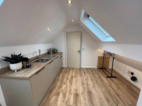a kitchen with white cabinets and a sink and a skylight at Garage loft conversion Killinchy in Killinchy