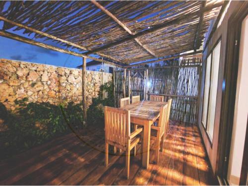 een terras met een houten tafel en stoelen bij Villa Nyota Zanzibar in Kidenga