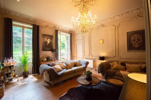 a living room with a couch and a chandelier at Historic manoir in Vire Normandy elegance in a semi-rural setting ideal for groups and families in Vire
