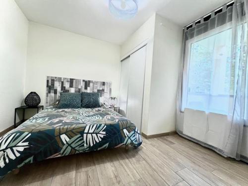 a bedroom with a bed and a large window at Spacieux T2 avec extérieur in Marignier