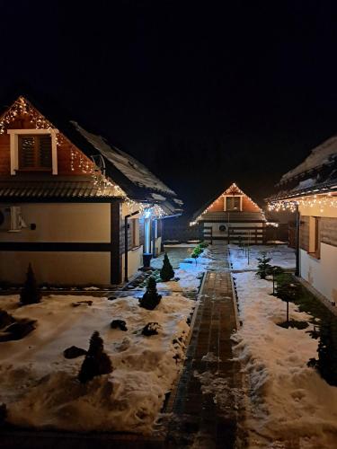 a yard covered in snow at night with lights at Całoroczne Domki Wypoczynkowe - Osada pod Górą in Ustrzyki Dolne