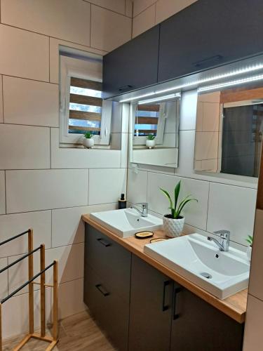 a bathroom with two sinks and two mirrors at Całoroczne Domki Wypoczynkowe - Osada pod Górą in Ustrzyki Dolne
