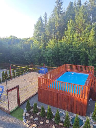 a pool with a wooden fence and a playground at Całoroczne Domki Wypoczynkowe - Osada pod Górą in Ustrzyki Dolne