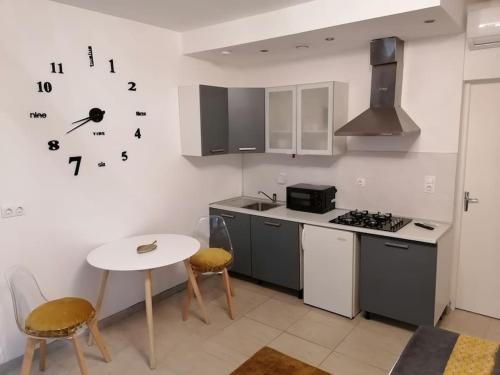 une cuisine avec une table et une cuisinière ainsi qu'une horloge murale. dans l'établissement Studio proche du centre-ville, à Carcassonne