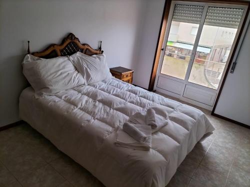 a large white bed in a bedroom with a door at Casa da Praia in Praia de Mira