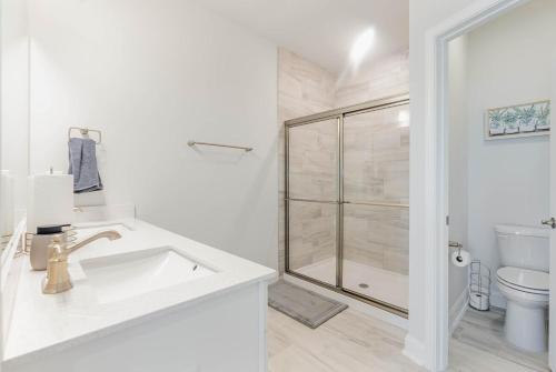 La salle de bains blanche est pourvue d'un lavabo et d'une douche. dans l'établissement Stylish Barefoot Townhome, Sleeps 10 NEW!, à Myrtle Beach