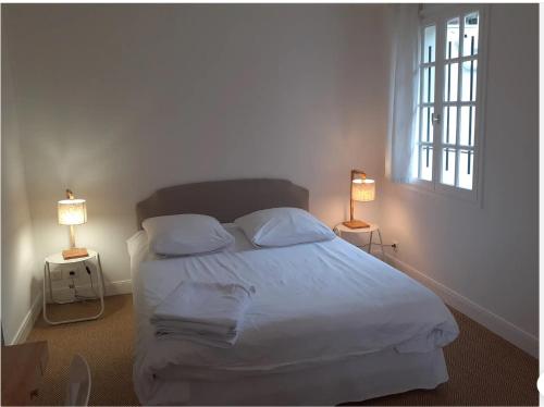 una camera da letto con un grande letto bianco con due lampade di Mendiska a Bayonne
