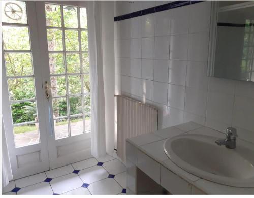 biała łazienka z umywalką i oknem w obiekcie Mendiska w Bajonnie