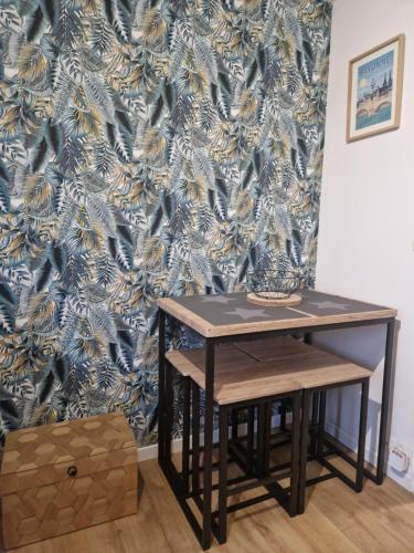 une table et un tabouret dans une pièce avec papier peint dans l'établissement Le victoruy, à Mont-de-Marsan