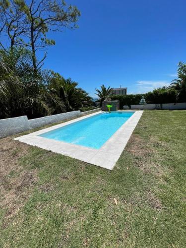 a swimming pool in a yard with a grass field at Visión ESCAPE Piriápolis in Piriápolis