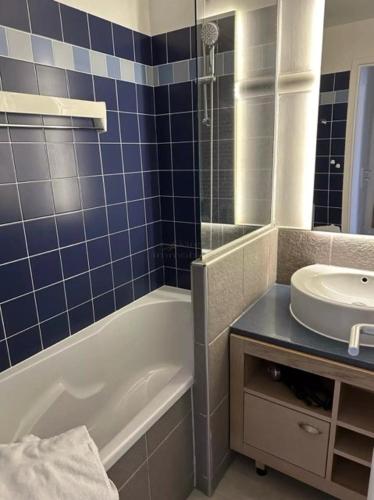 La salle de bains est pourvue de carrelage bleu, d'une baignoire et d'un lavabo. dans l'établissement Residence de la Plage Pierre et Vacances, au Crotoy