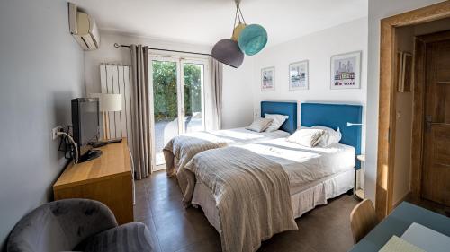 a hotel room with two beds and a television at VILLA TIMAUTINE Cannes in Peymeinade