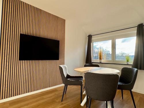 Habitación con mesa, sillas y TV en la pared. en Modernes City Apartment nahe Hbf, en Emden