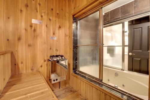 baño con paredes de madera, ventana y bañera en Iron River Retreat with Sauna Walk to Ski Brule!, en Iron River