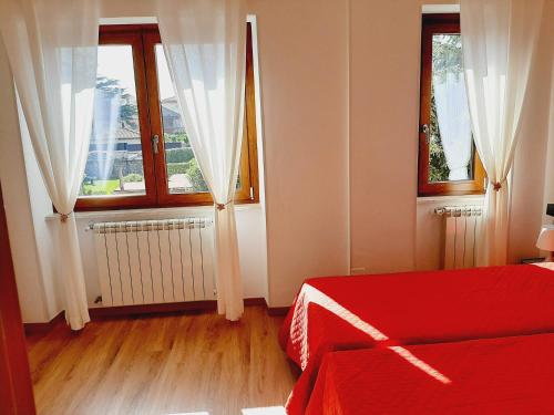a bedroom with a red bed and two windows at Casa Annalisa in Scauri