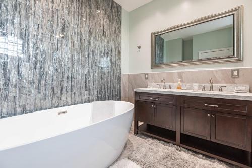 La salle de bains est pourvue d'une baignoire, d'un lavabo et d'un miroir. dans l'établissement Tropical Oasis with Heated Pool, à Boynton Beach