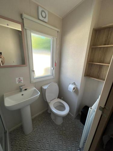 uma casa de banho com um lavatório, um WC e uma janela. em Lovely 2-Bed Luxury Caravan in Newquay em Newquay
